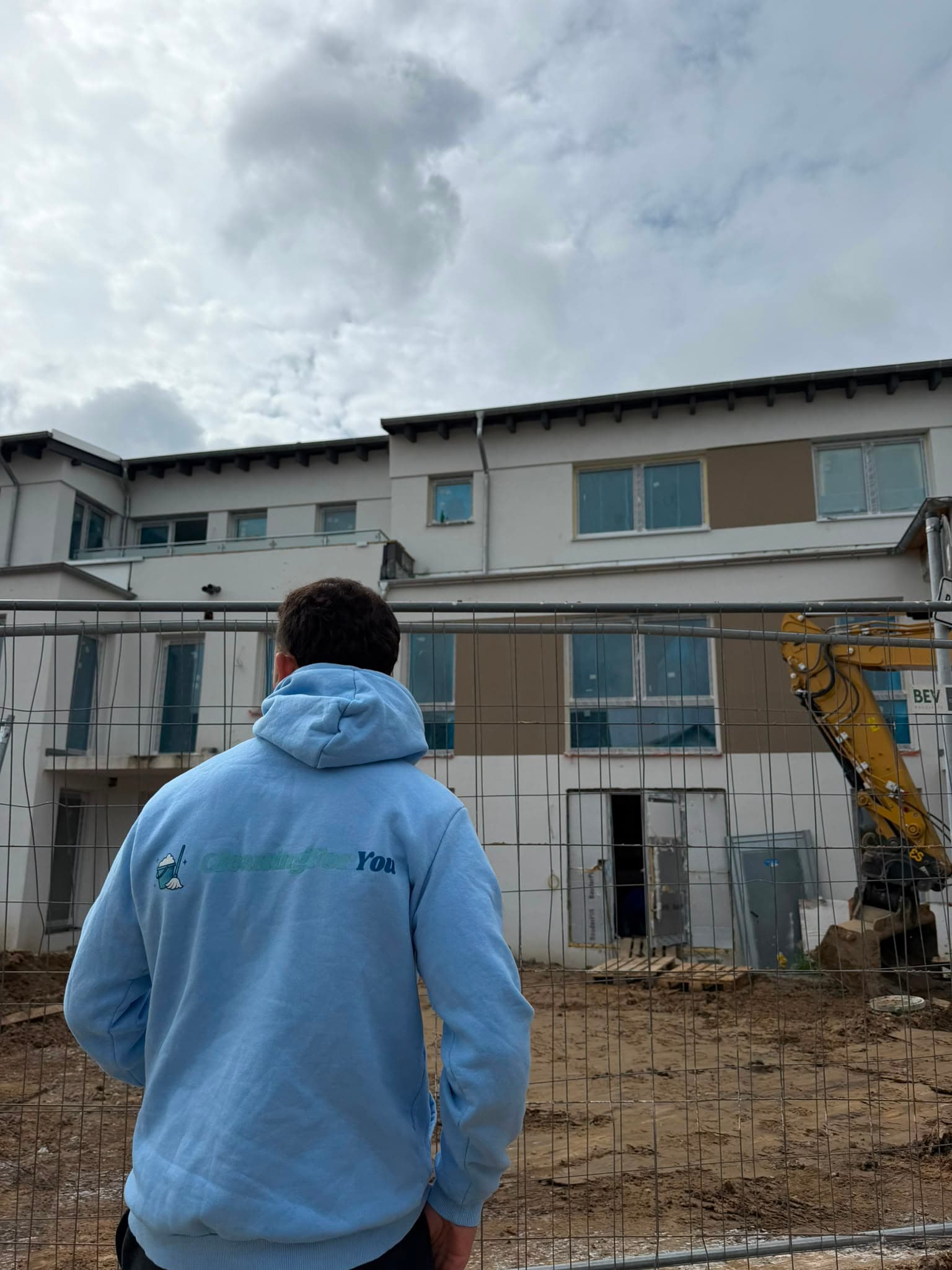 Mitarbeiter im CleaningForYou-Hoodie vor einem Objekt auf der Baustelle